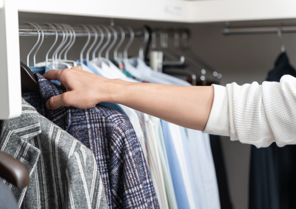 ウォークインクローゼットで服を選ぶ若い男性(ファッション・コーディネート)